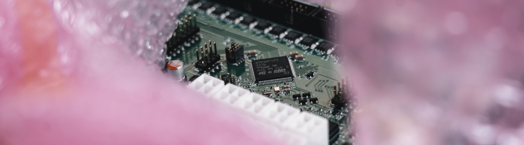 SMD‑ und THT‑bestückte Leiterplatte, teilweise umgeben von einer rosa ESD‑Schutztüte