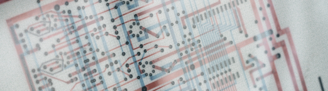 Historisches, rot‑blau geklebtes Platinenlayout als Symbol früher Elektronikfertigung